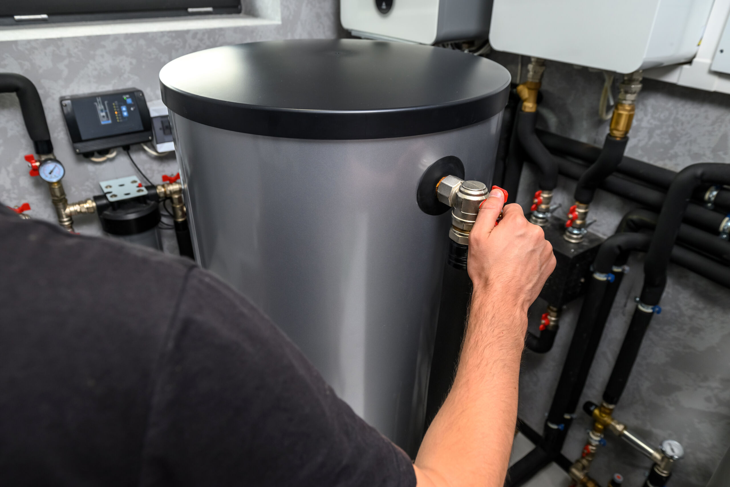 Modern electric boiler room in the house. Equipment for water heating system with automatic control unit. Close-up of a man's hand